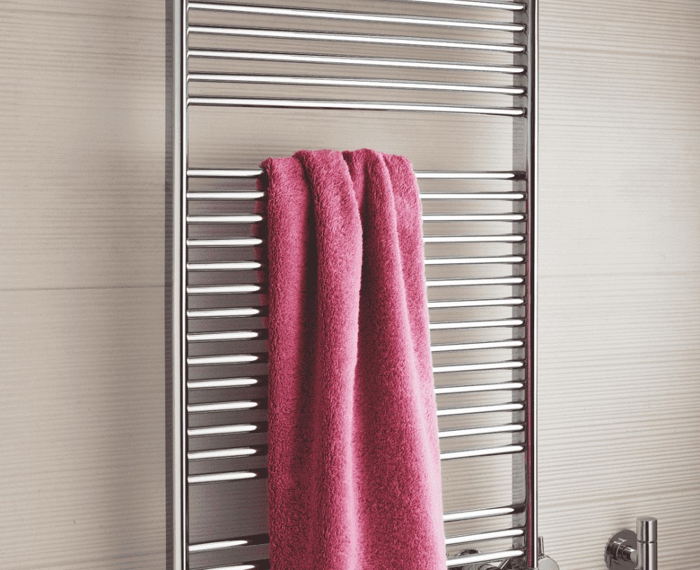 Хромированное водяное полотенцесушитель, с металлическими трубками и краном. На сушке висит полотенце розового цвета, оно помогает эффективно его высушить. Сама полотенцесушительная прикреплена к плитке на стене в ванной комнате